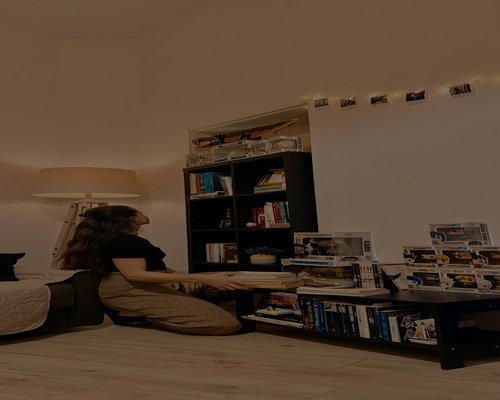 A warmly lit room with a person reading a book near a lamp